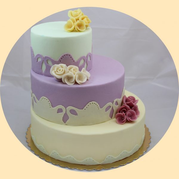 Eltolt szintes három emeletes torta fehér, lila és halványzöld színekben, hehér lila és sérga marcipán virágcsokor díszítéssel.